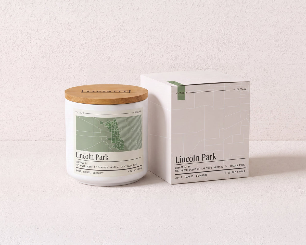 Lincoln Park 9 oz soy candle and its gift box, both printed with a Chicago neighborhood map, on a cream plaster surface