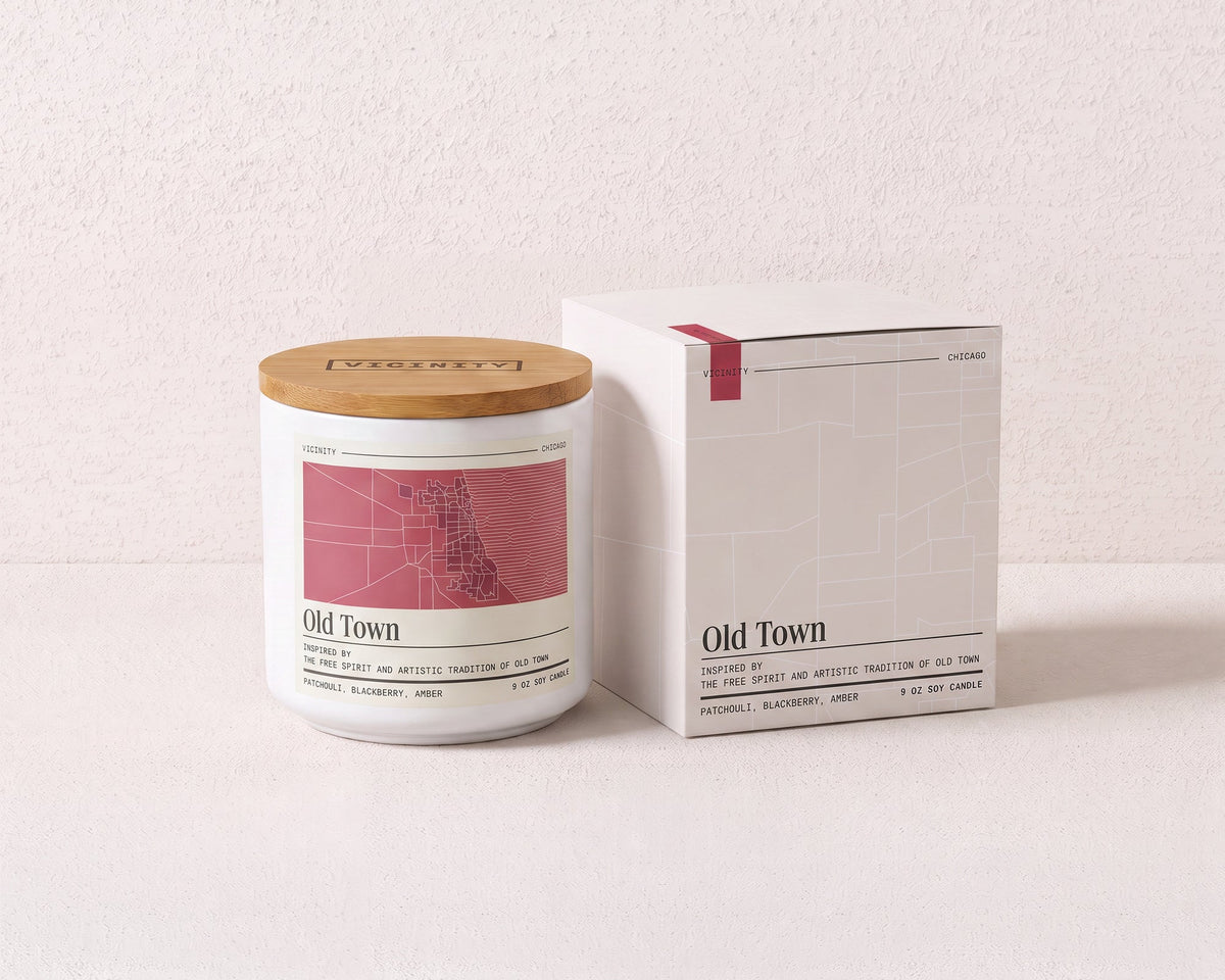 Old Town 9 oz soy candle and its gift box, both printed with a Chicago neighborhood map, on a cream plaster surface