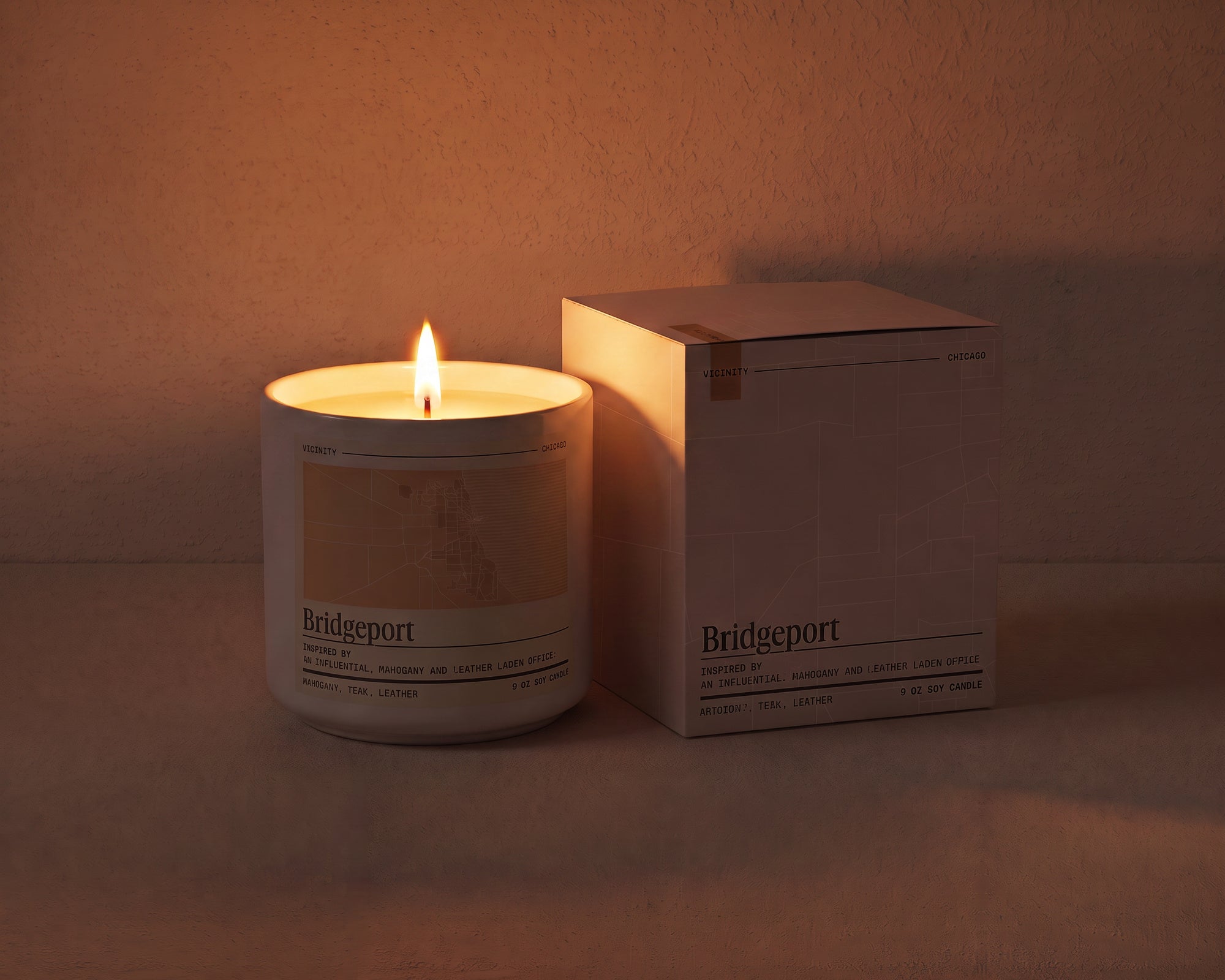 Bridgeport 9 oz soy candle and its gift box, both printed with a Chicago neighborhood map, on a cream plaster surface