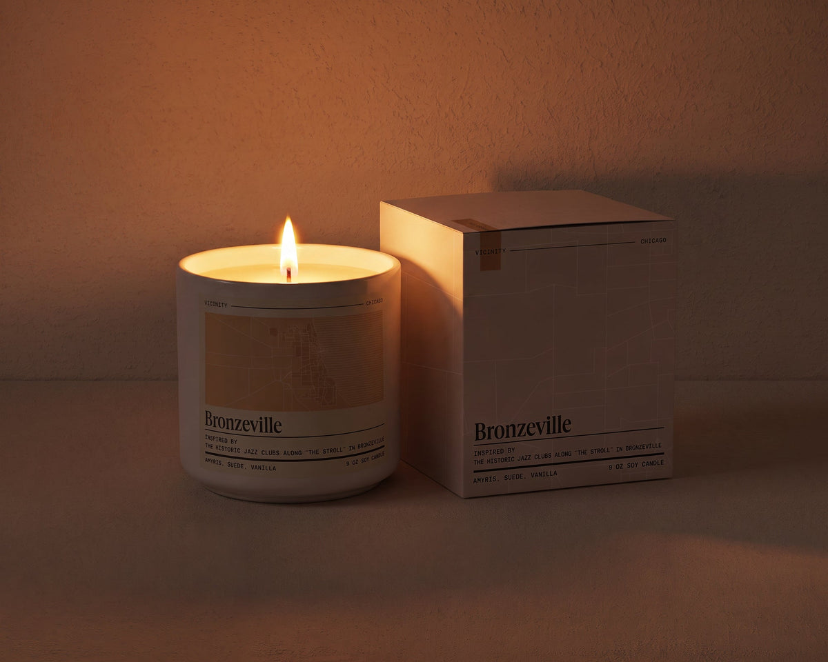 Bronzeville 9 oz soy candle lit beside its gift box, the room lit only by the candle flame