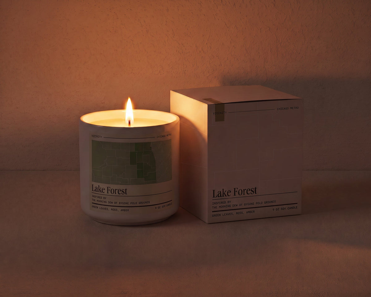 Lake Forest 9 oz soy candle lit beside its gift box, the room lit only by the candle flame