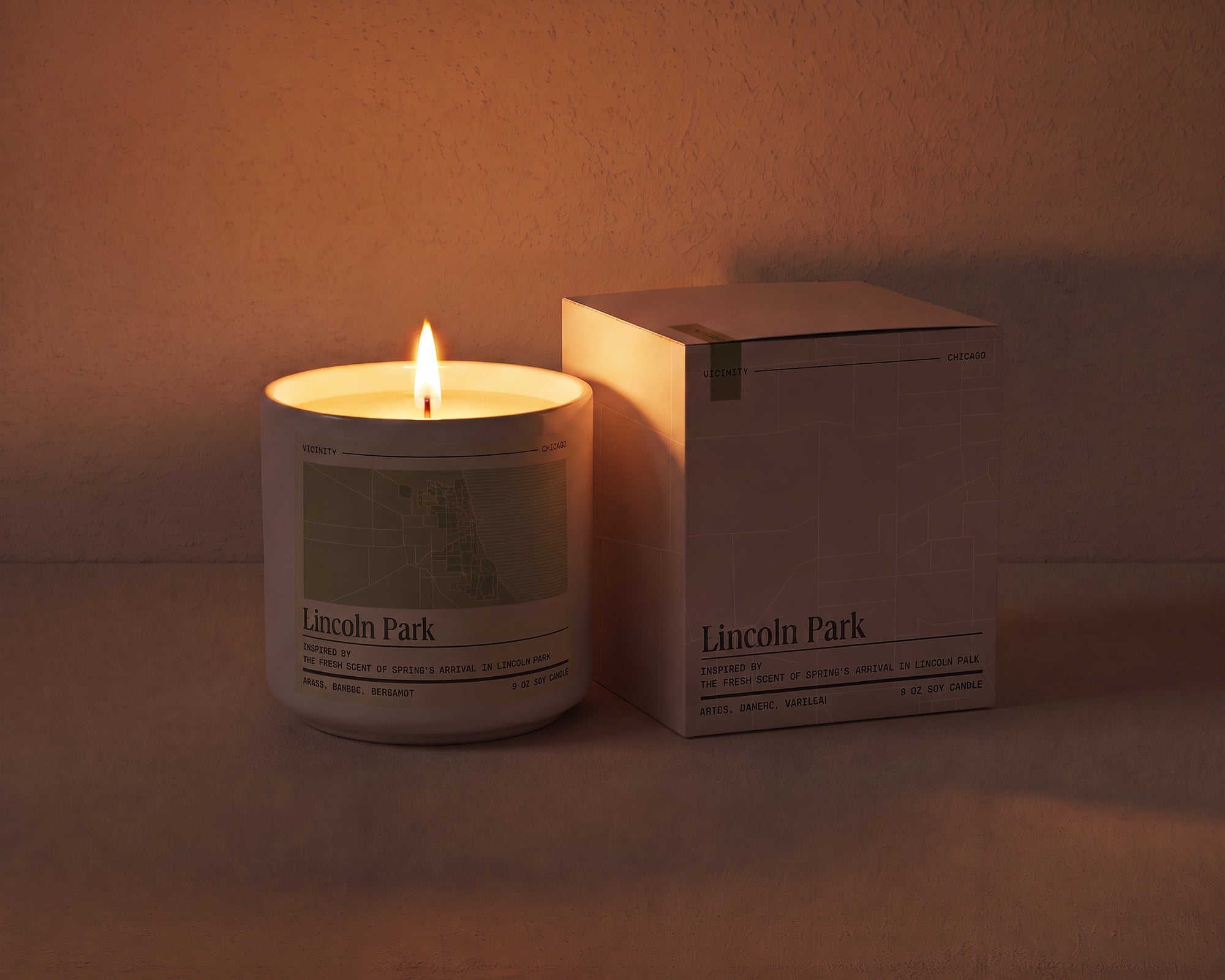 Lincoln Park 9 oz soy candle and its gift box, both printed with a Chicago neighborhood map, on a cream plaster surface