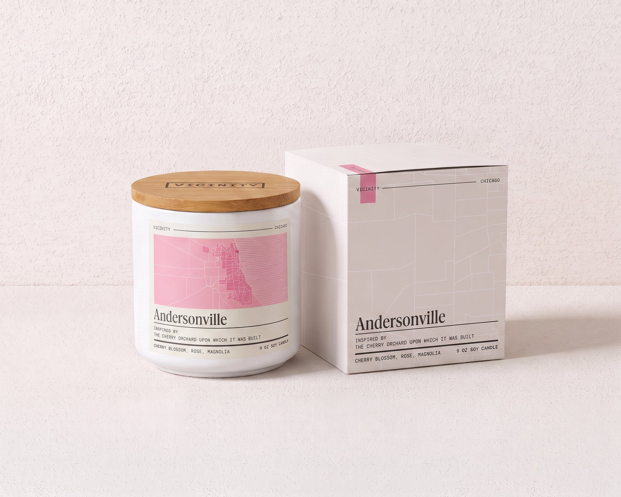 Andersonville 9 oz soy candle and its gift box, both printed with a Chicago neighborhood map, on a cream plaster surface
