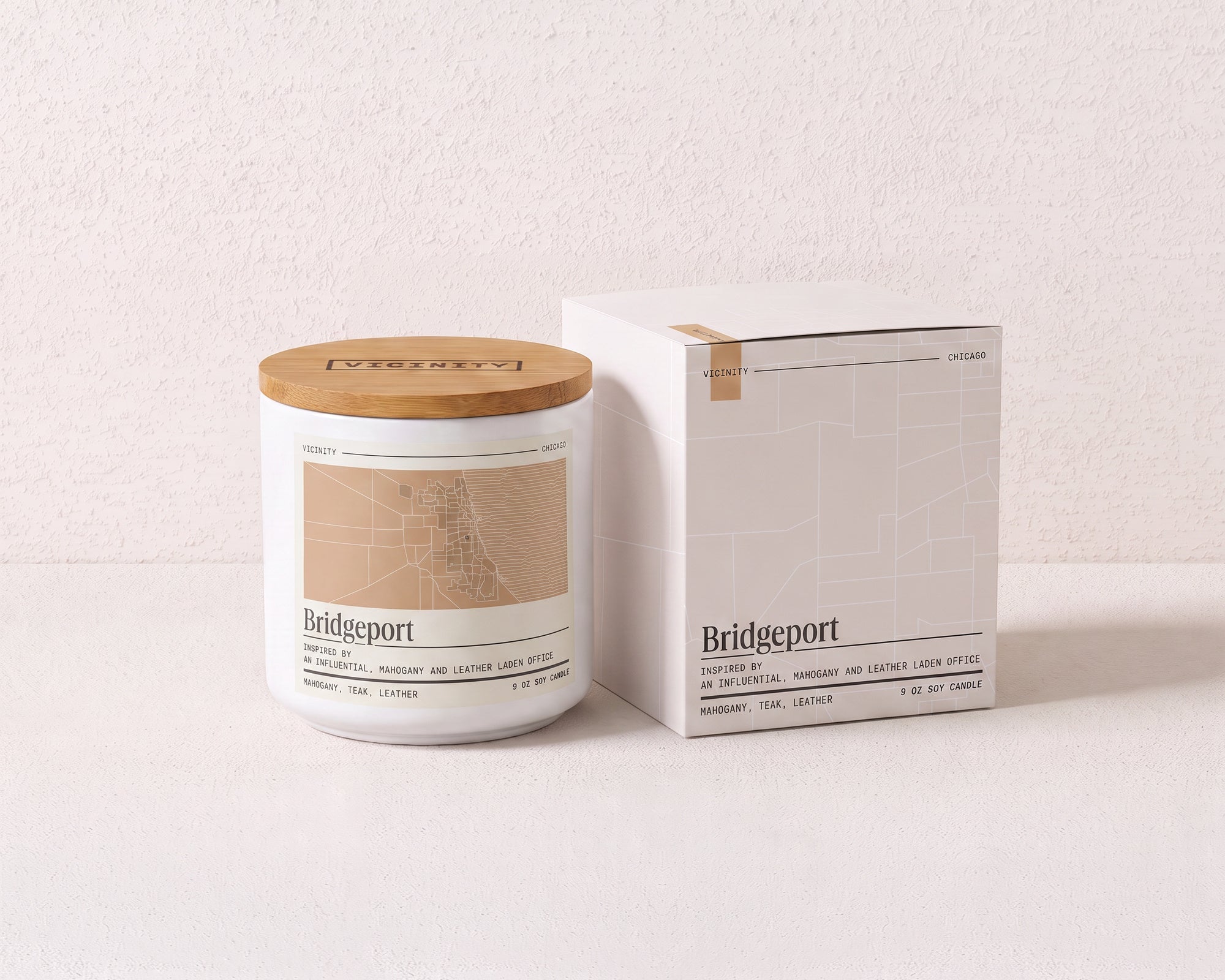 Bridgeport 9 oz soy candle and its gift box, both printed with a Chicago neighborhood map, on a cream plaster surface