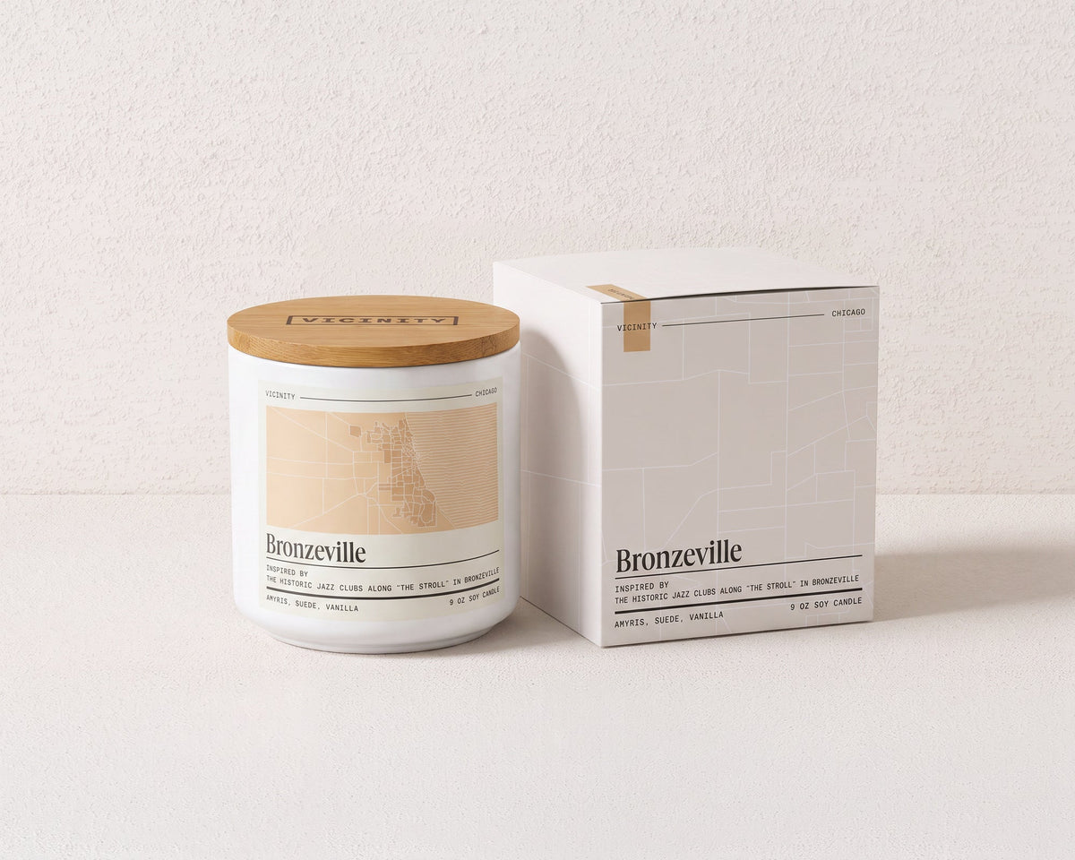 Bronzeville 9 oz soy candle and its gift box, both printed with a Chicago neighborhood map, on a cream plaster surface