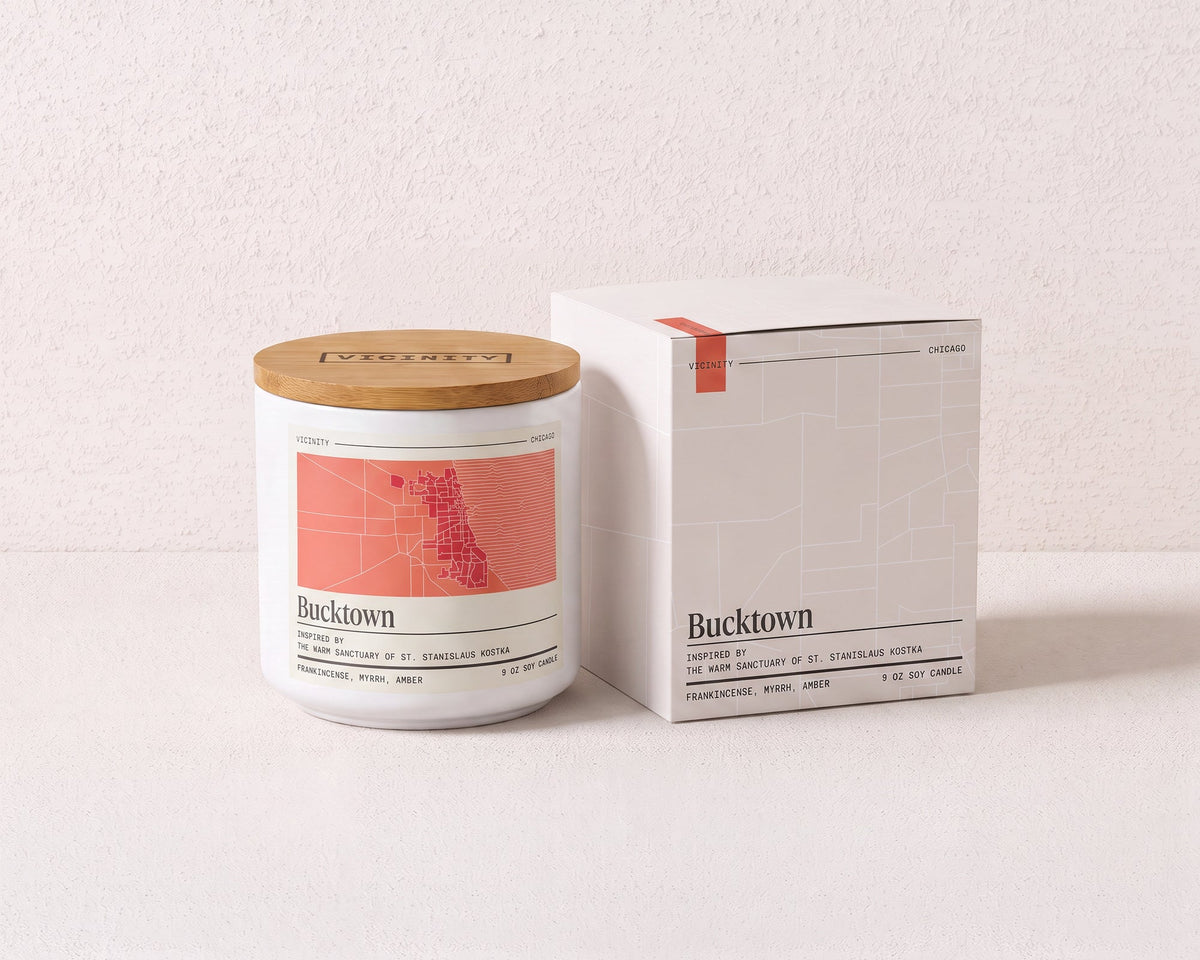 Bucktown 9 oz soy candle and its gift box, both printed with a Chicago neighborhood map, on a cream plaster surface