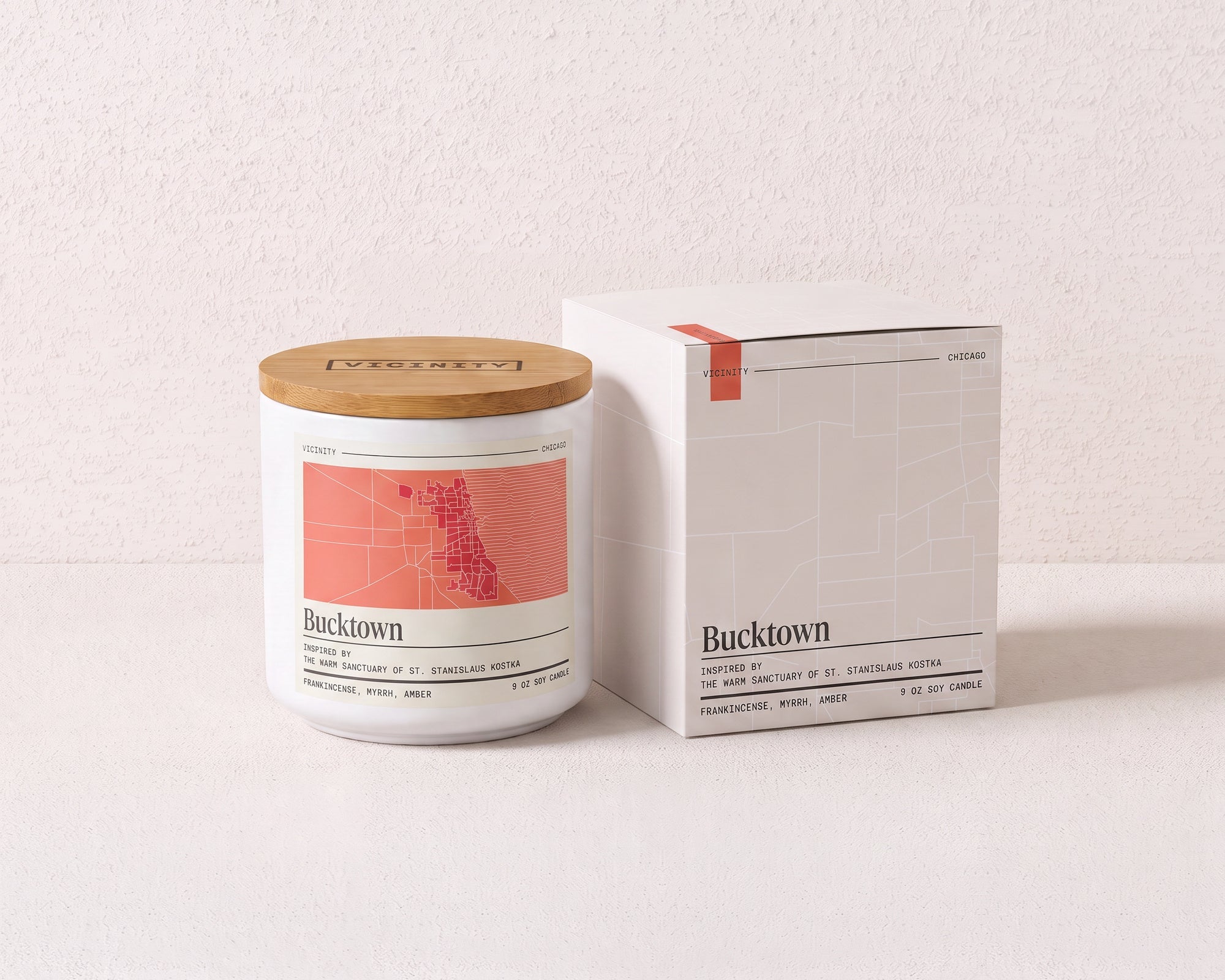 Bucktown 9 oz soy candle and its gift box, both printed with a Chicago neighborhood map, on a cream plaster surface