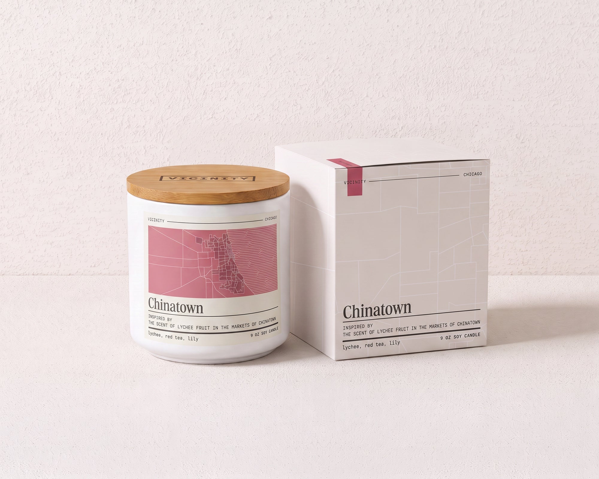 Chinatown 9 oz soy candle and its gift box, both printed with a Chicago neighborhood map, on a cream plaster surface