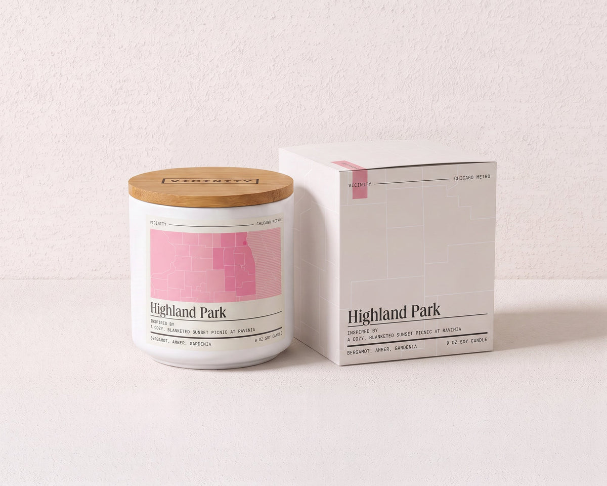 Highland Park 9 oz soy candle and its gift box, both printed with a Chicago neighborhood map, on a cream plaster surface