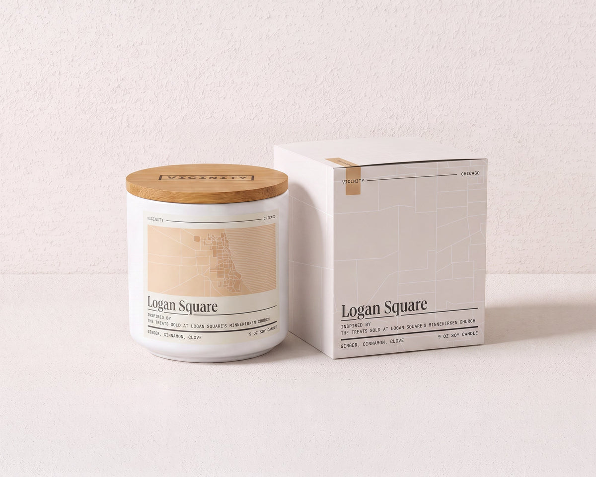 Logan Square 9 oz soy candle and its gift box, both printed with a Chicago neighborhood map, on a cream plaster surface