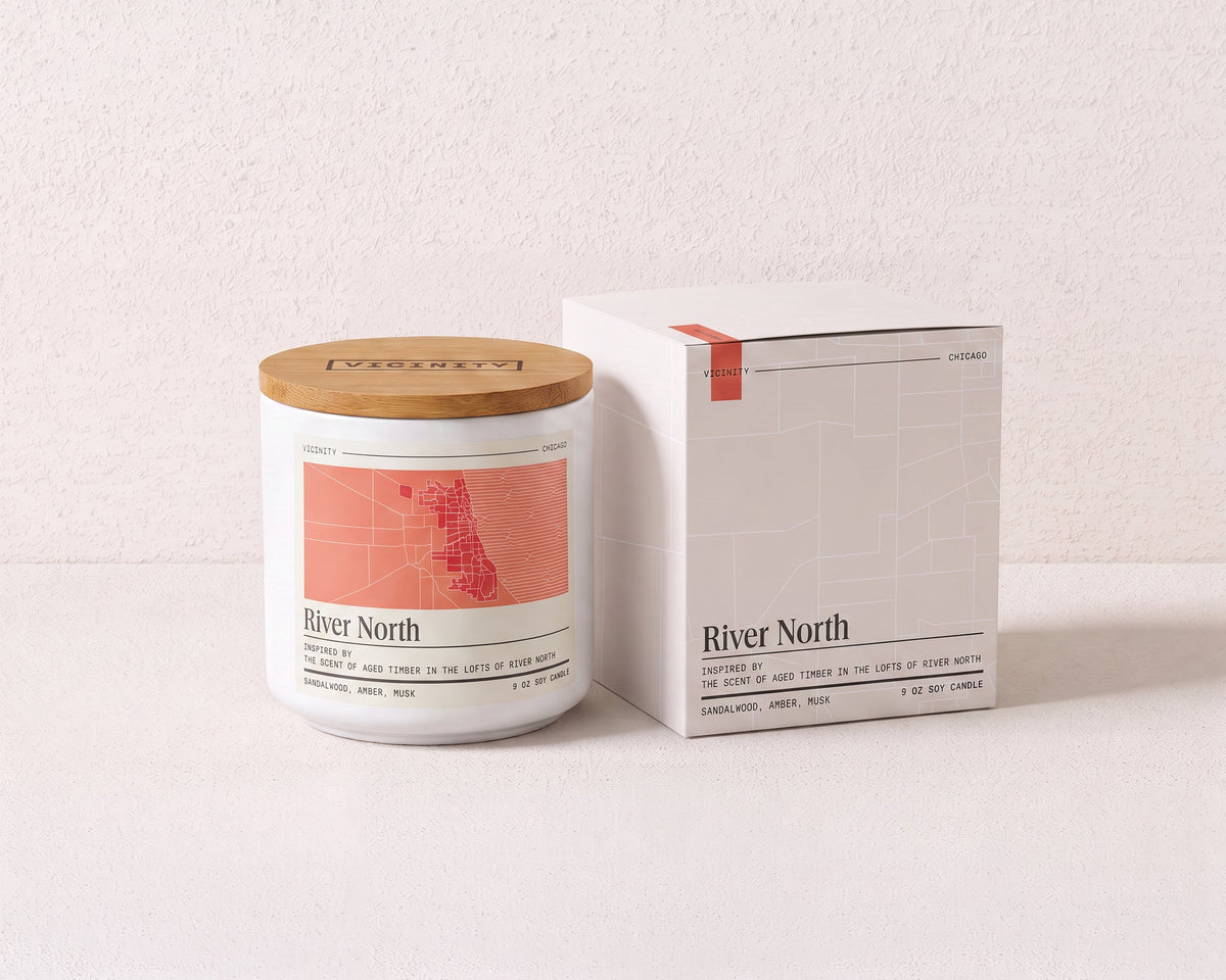 River North 9 oz soy candle and its gift box, both printed with a Chicago neighborhood map, on a cream plaster surface
