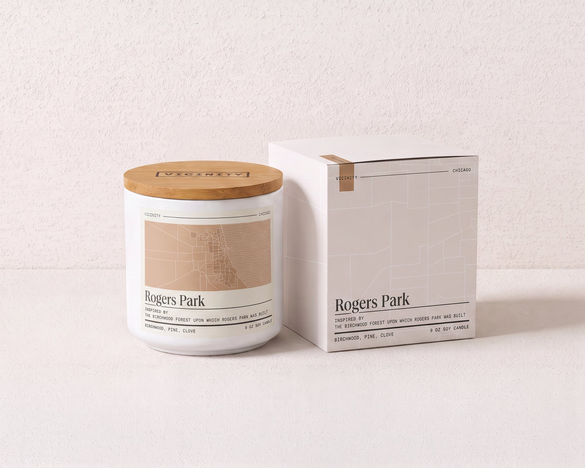 Rogers Park 9 oz soy candle and its gift box, both printed with a Chicago neighborhood map, on a cream plaster surface