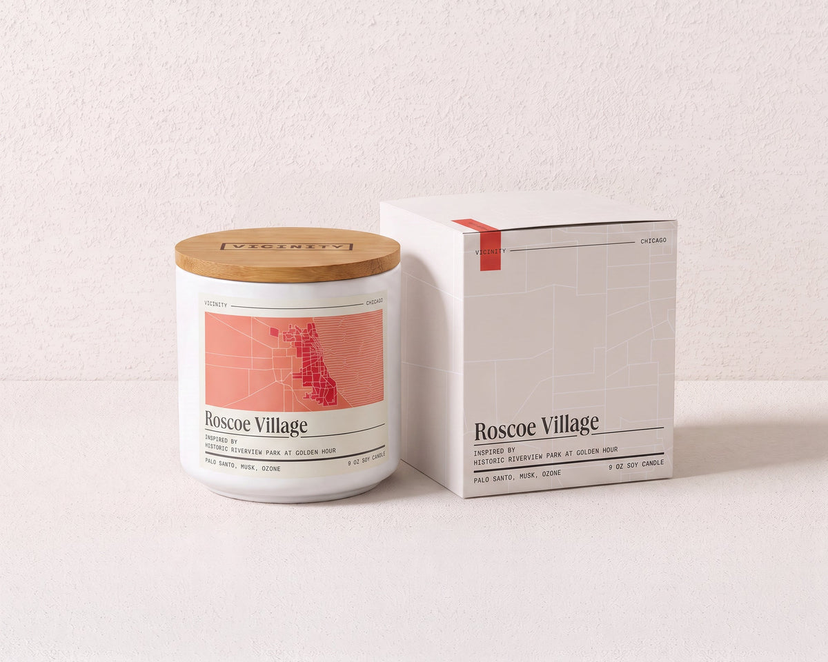 Roscoe Village 9 oz soy candle and its gift box, both printed with a Chicago neighborhood map, on a cream plaster surface