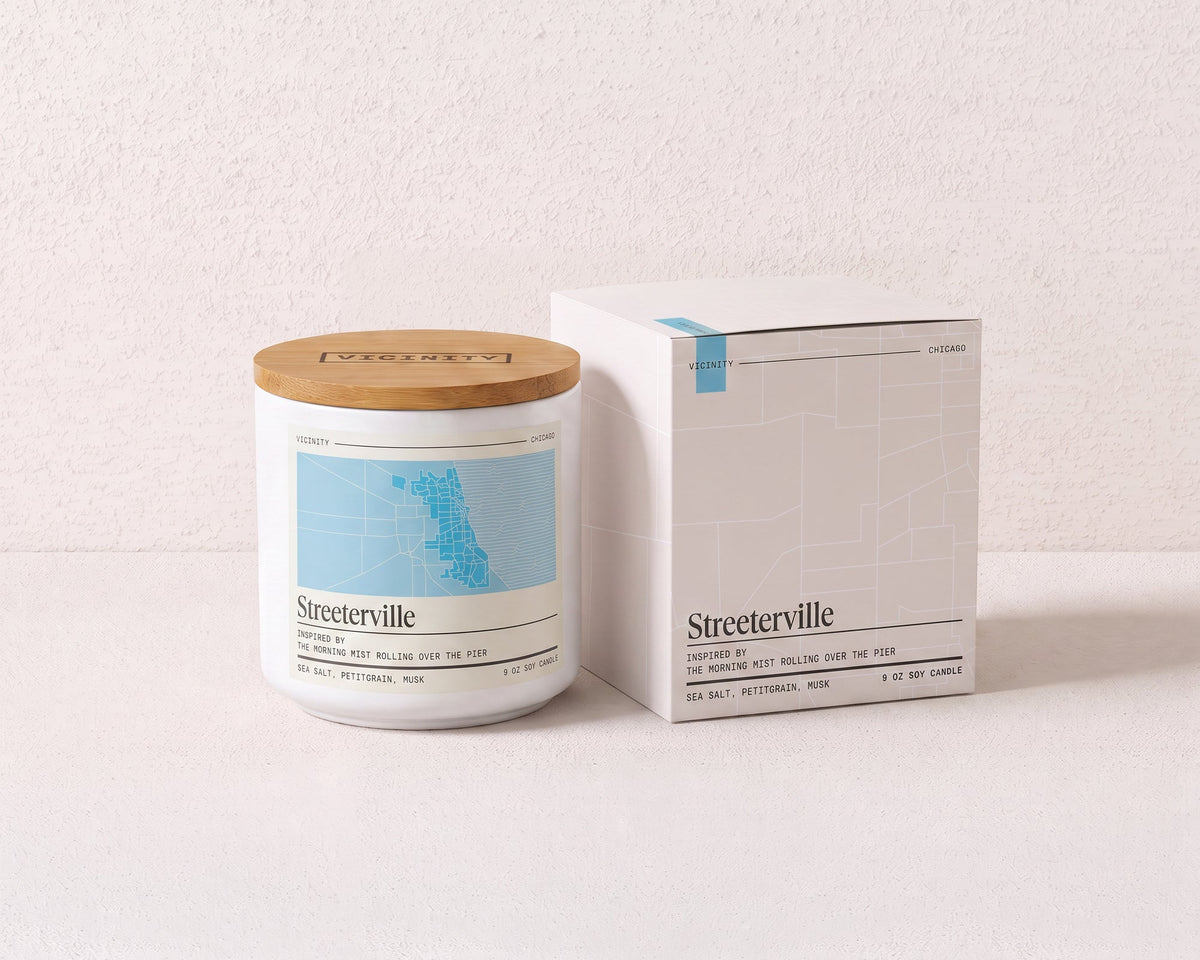 Streeterville 9 oz soy candle and its gift box, both printed with a Chicago neighborhood map, on a cream plaster surface