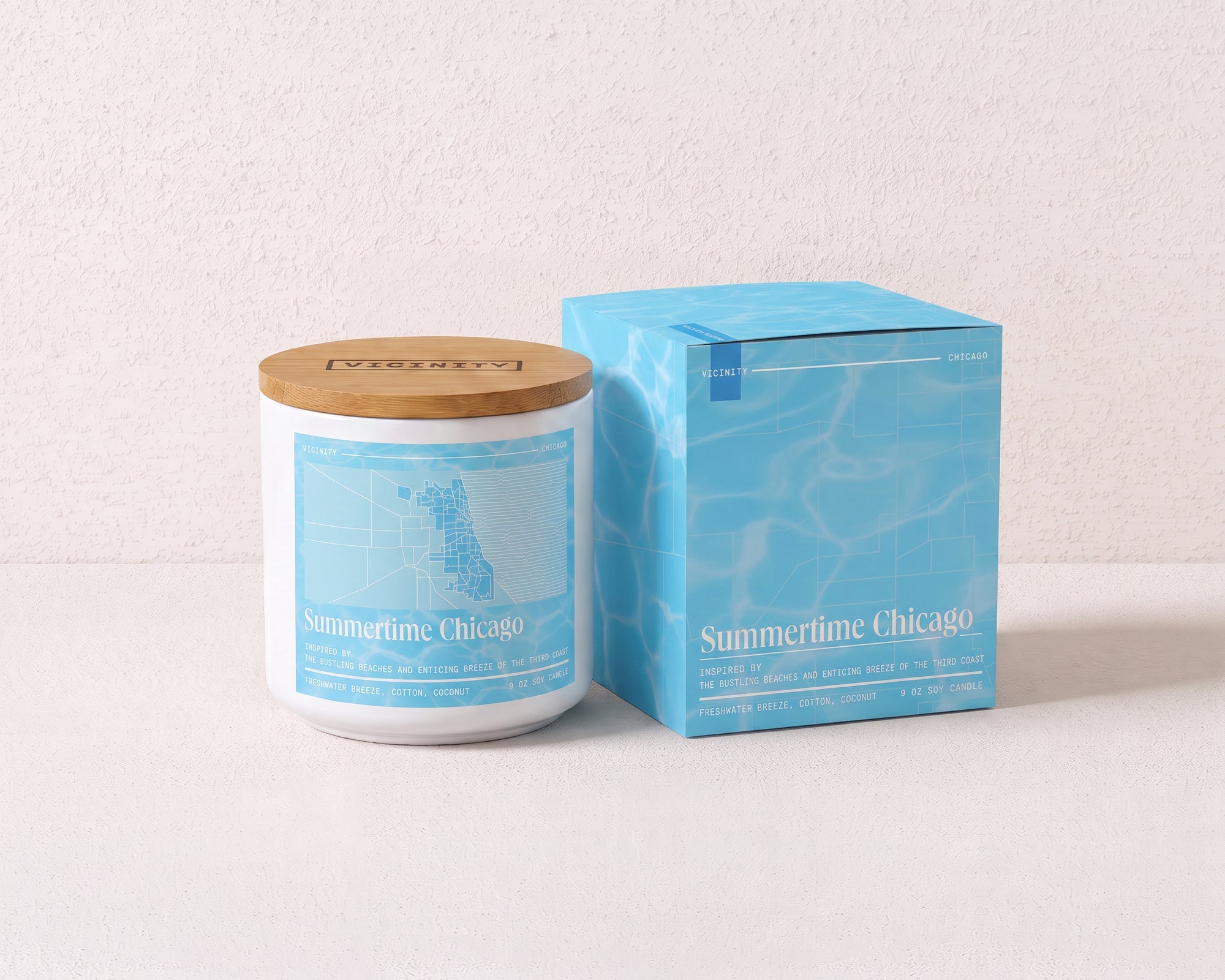 Summertime Chicago 9 oz soy candle and its gift box, both printed with a Chicago neighborhood map, on a cream plaster surface