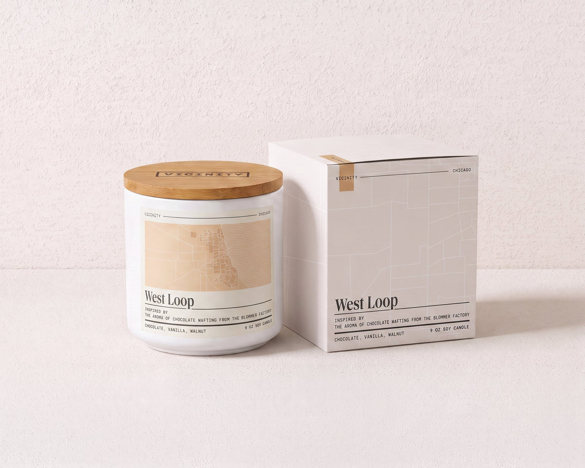 West Loop 9 oz soy candle and its gift box, both printed with a Chicago neighborhood map, on a cream plaster surface