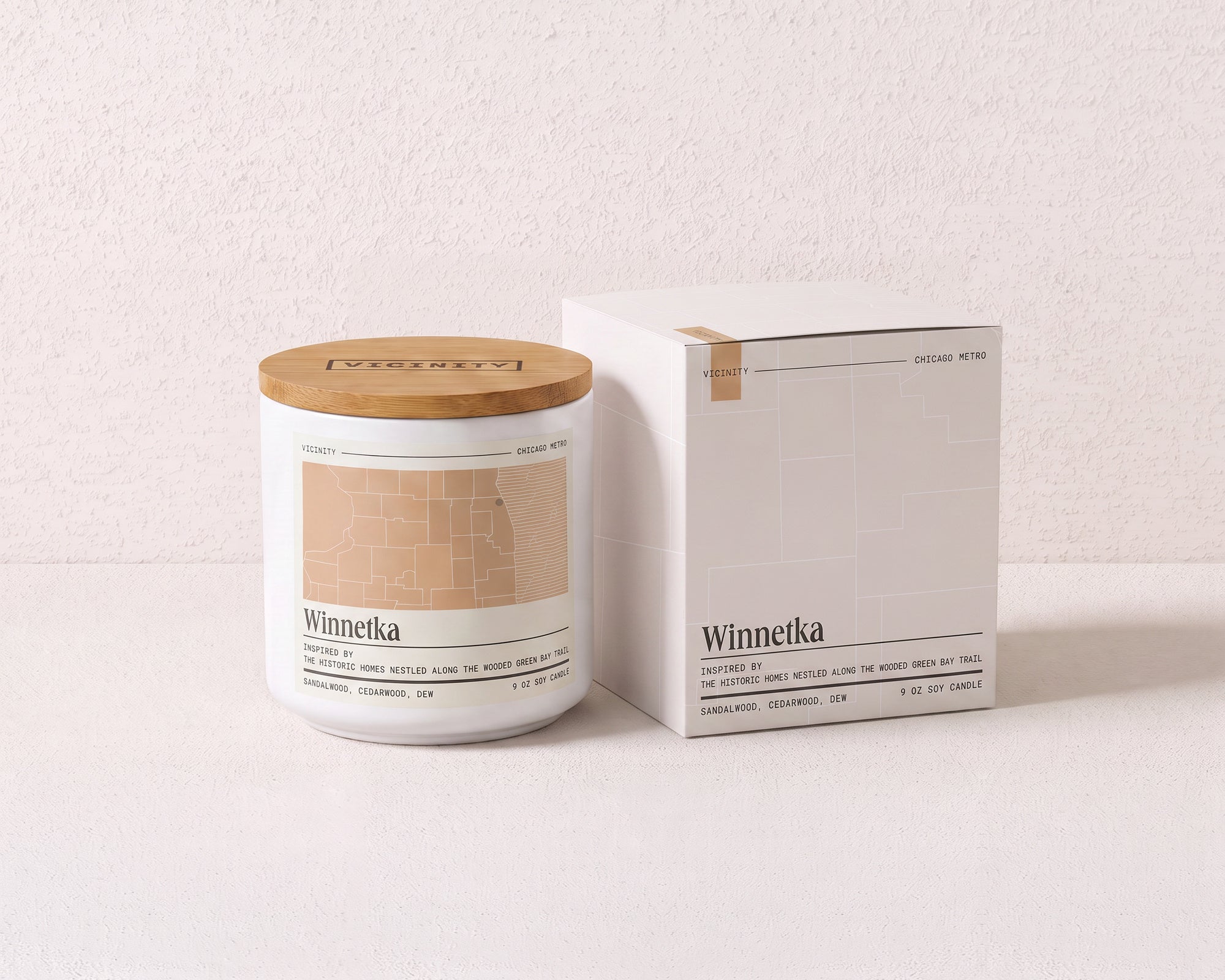 Winnetka 9 oz soy candle and its gift box, both printed with a Chicago neighborhood map, on a cream plaster surface