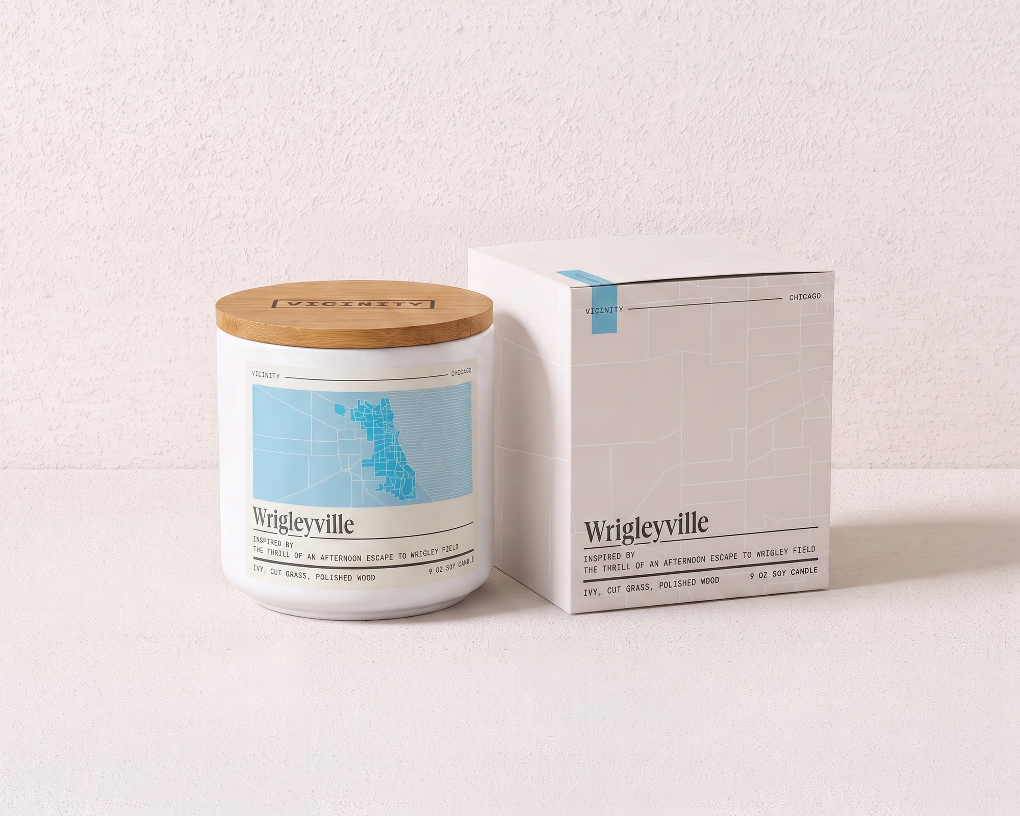 Wrigleyville 9 oz soy candle and its gift box, both printed with a Chicago neighborhood map, on a cream plaster surface